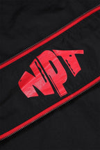 Detail of Black and Red NPT logo on Baby Gang zip track top, showcasing bold design and stylish athletic wear.