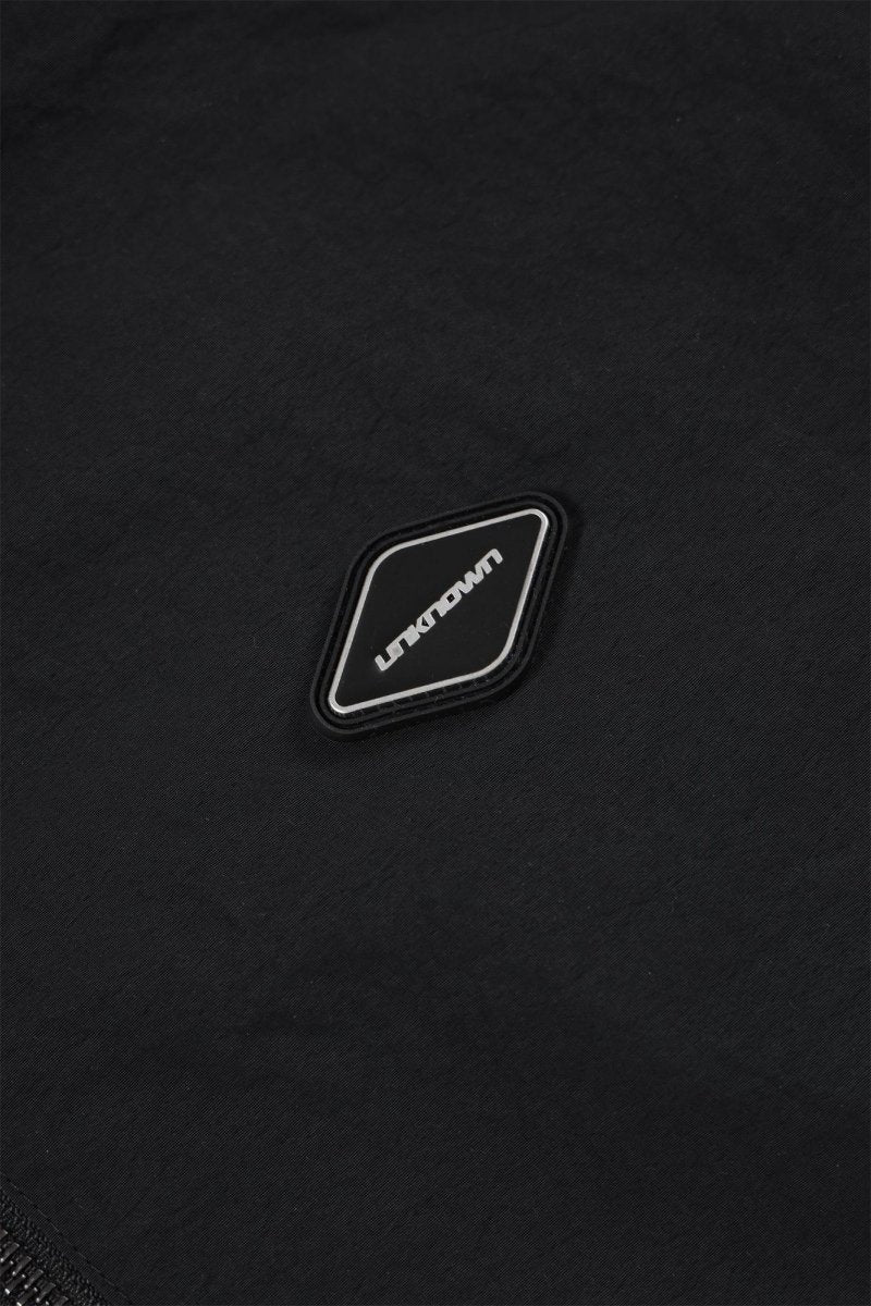 Close-up of the black fabric with a black and white logo patch on the Black/Red NPT Baby Gang Zip Track Top.