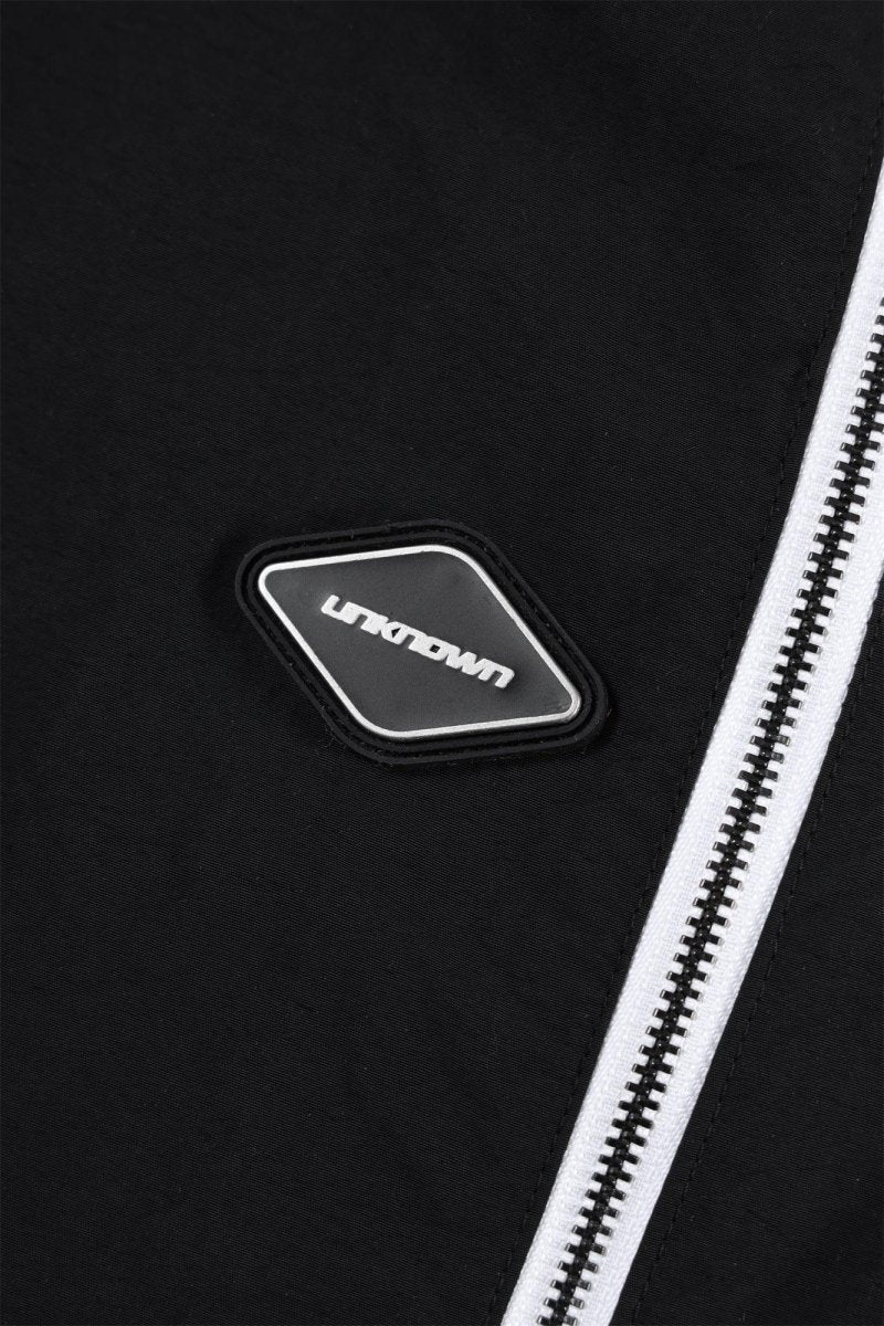 Close-up of the logo on the Black/White NPT Baby Gang Zip Track Pants by Unknown, featuring a sleek design.