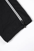 Close-up of the black ankle area of Black / White NPT Baby Gang Zip Track Pants with zip detail.