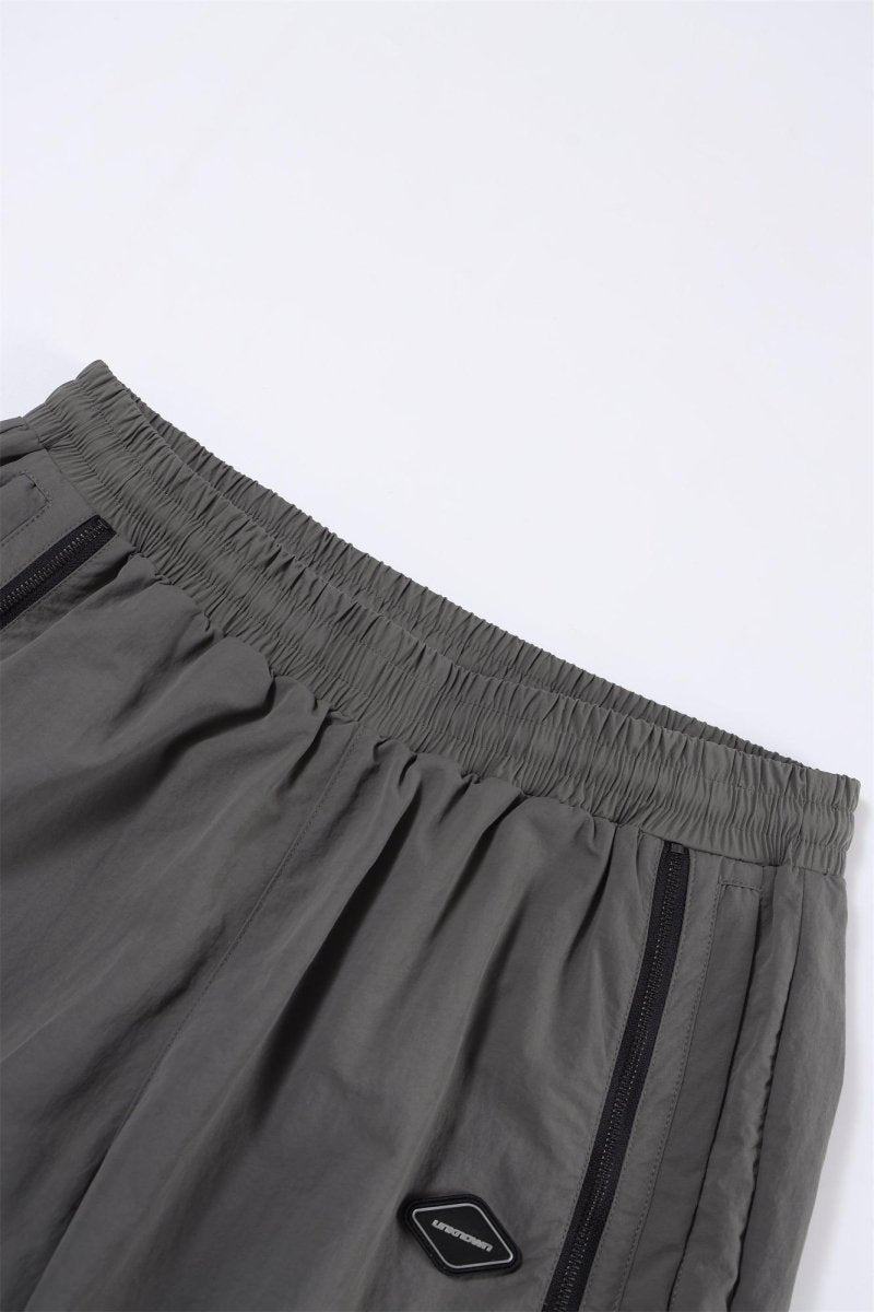 Grey and black NPT Simba La Rue zip track pants with elastic waistband and side pockets, showcasing casual athletic style.