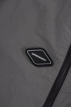 Close-up of a grey fabric with a black zipper and branded logo on the Grey/Black NPT Simba La Rue Zip Track Pants.