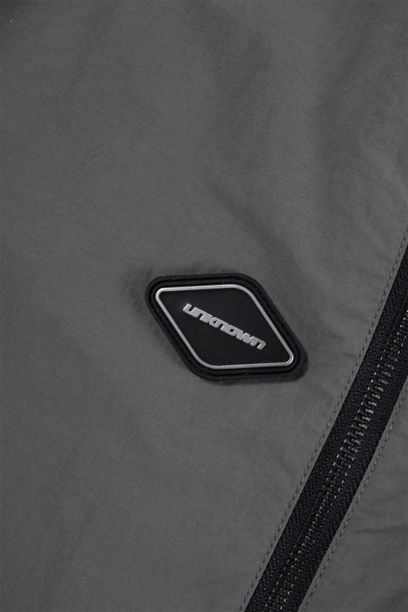 Close-up of a grey fabric with a black zipper and branded logo on the Grey/Black NPT Simba La Rue Zip Track Pants.