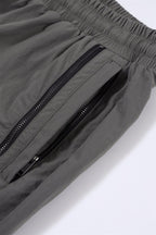 Close-up of grey NPT Simba La Rue zip track pants showing elastic waistband and zippered pocket details.