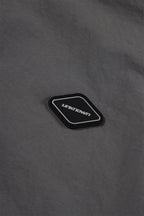 Close-up of Unknown brand logo patch on grey fabric of the Grey/Black NPT Simba La Rue Zip Track Top.