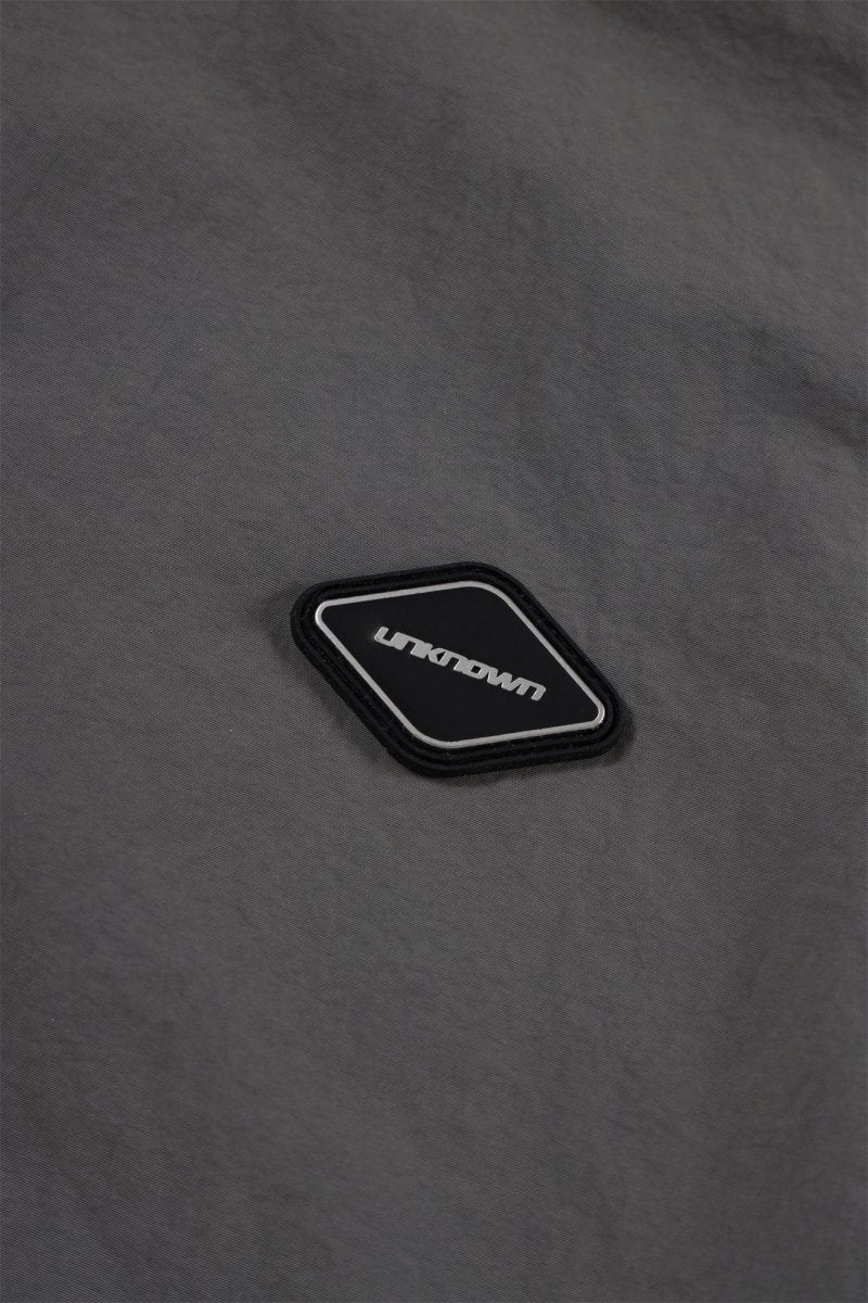 Close-up of Unknown brand logo patch on grey fabric of the Grey/Black NPT Simba La Rue Zip Track Top.