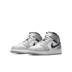 Air Jordan 1 Mid Light Smoke Grey shoes with grey and white leather, featuring a black Swoosh and modern design.