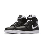 Air Jordan 1 Retro Mid Black White sneakers with leather upper, nylon tongue, and embroidered Jumpman logo.