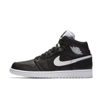 Air Jordan 1 Retro Mid in black leather with white Swoosh and Wings logo, showcasing a sleek, monochromatic design.