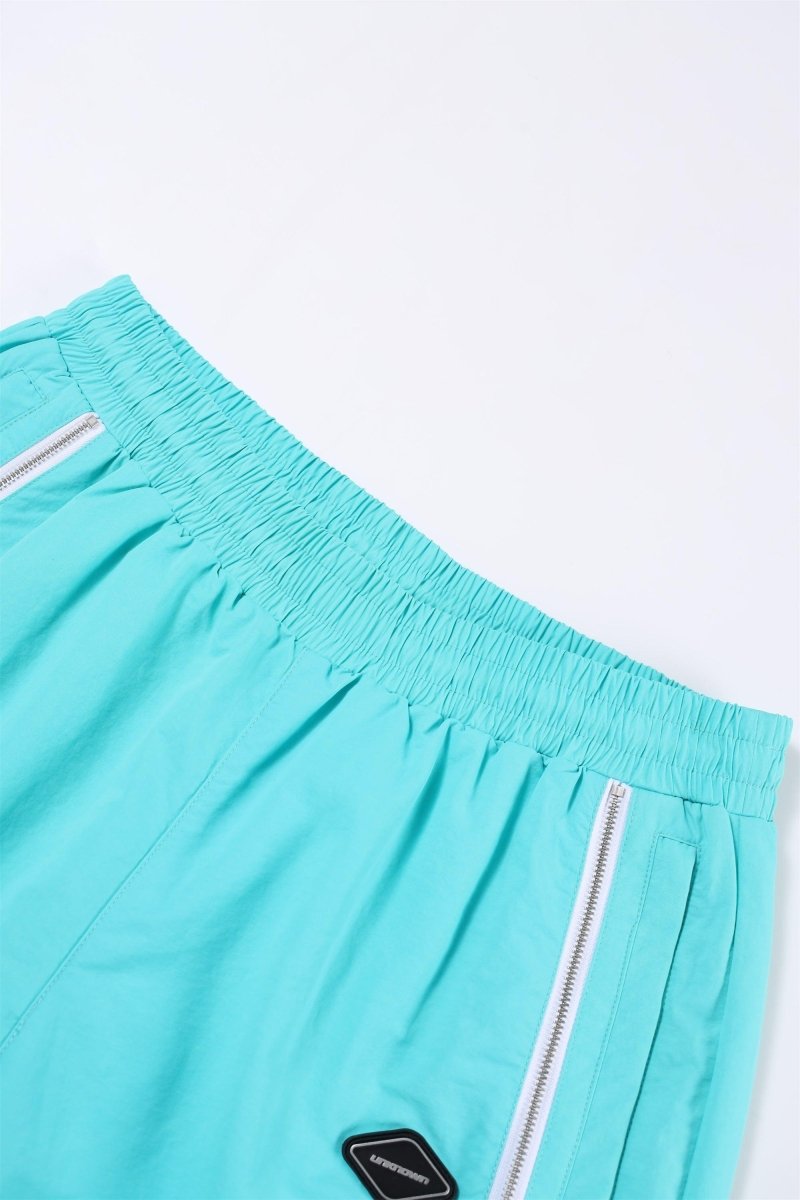 Mint and white Simba La Rue zip track pants close-up view of waistband and side zippers.