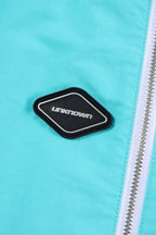 Close-up of the Unknown brand logo on mint and white zip track pants by Simba La Rue.