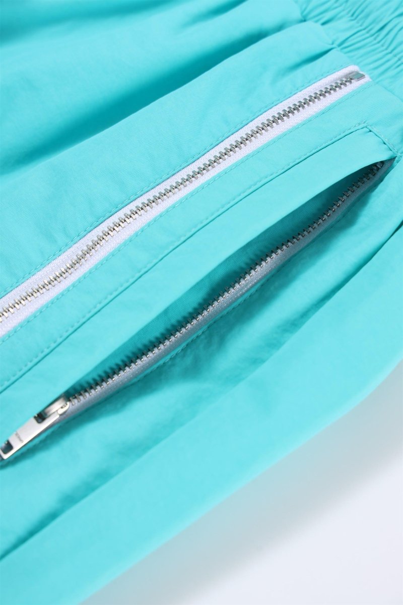 Detail of the zippered pocket on Mint / White NPT Simba La Rue Zip Track Pants, showcasing the aqua and white color.