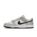Nike Dunk Low Light Iron Ore sneakers with grey and white leather, glossy black Swoosh, and red accent detail.
