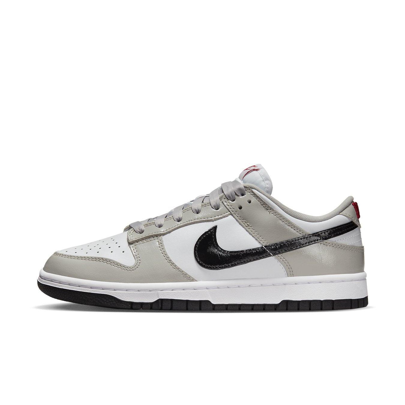 Nike Dunk Low Light Iron Ore sneakers with grey and white leather, glossy black Swoosh, and red accent detail.