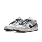 Nike Dunk Low Light Smoke Grey women's sneakers with black Swoosh and gray accents on a white leather base.