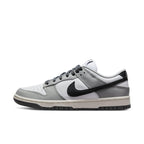 Nike Dunk Low Light Smoke Grey women’s sneaker featuring white leather base and contrasting black Swoosh.