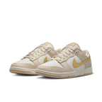Nike Dunk Low Phantom Metallic Gold sneakers in white and beige with yellow accents and clean design.
