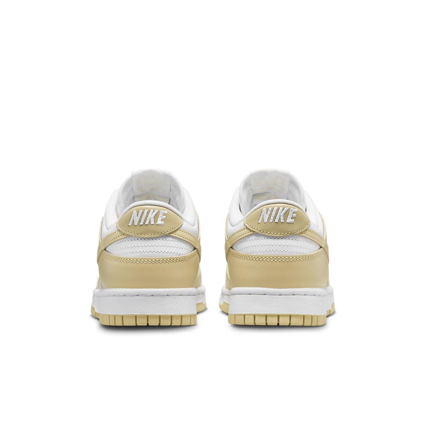 Retro Nike Dunk Low Team Gold sneakers in white and light yellow with Nike branding at the heel.