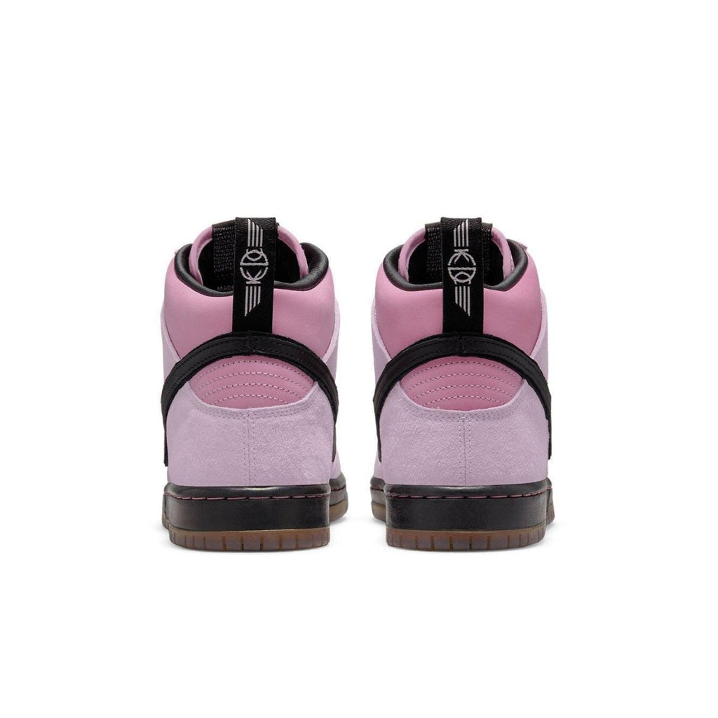 Nike SB Dunk High Pro KCDC in pink suede, featuring a black strap and gum sole, showcasing the back view.