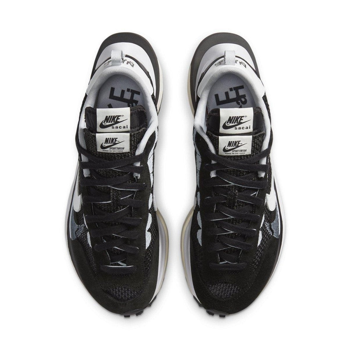 Top view of Nike VaporWaffle sacai sneakers in black and white with double laces and logo detail.